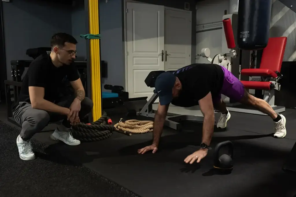 Coach supervisant un exercice de gainage réalisé par une adhérente